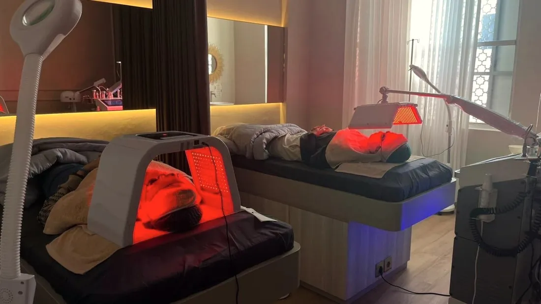Ruang perawatan dengan panel LED light therapy merah di atas bed treatment