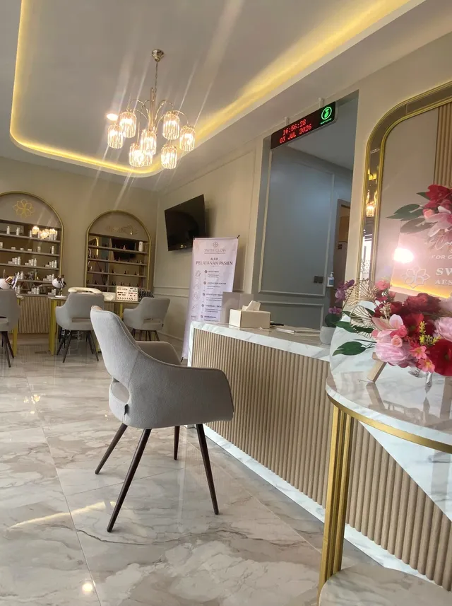 Lounge Swiss Glow dengan chandelier kristal, rak display berbentuk arch, dan lantai marmer