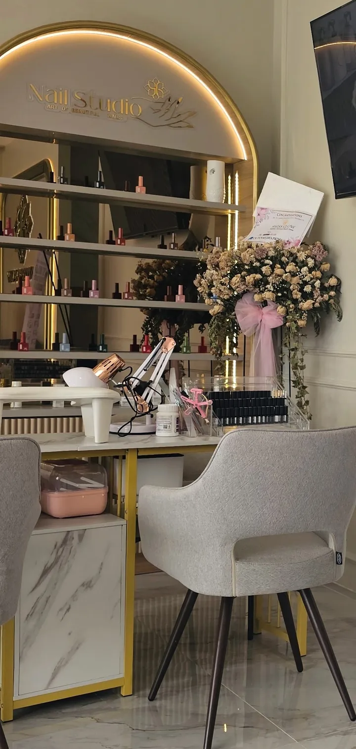 Nail studio berbingkai arch dengan rak warna kuteks dan kursi abu-abu