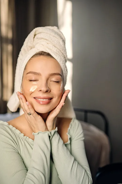 Perempuan tersenyum merawat kulit wajah dengan skincare
